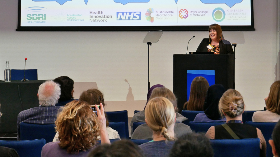 A photo of Emma Crookes on stage delivering a speech to the audience, who are in the foreground