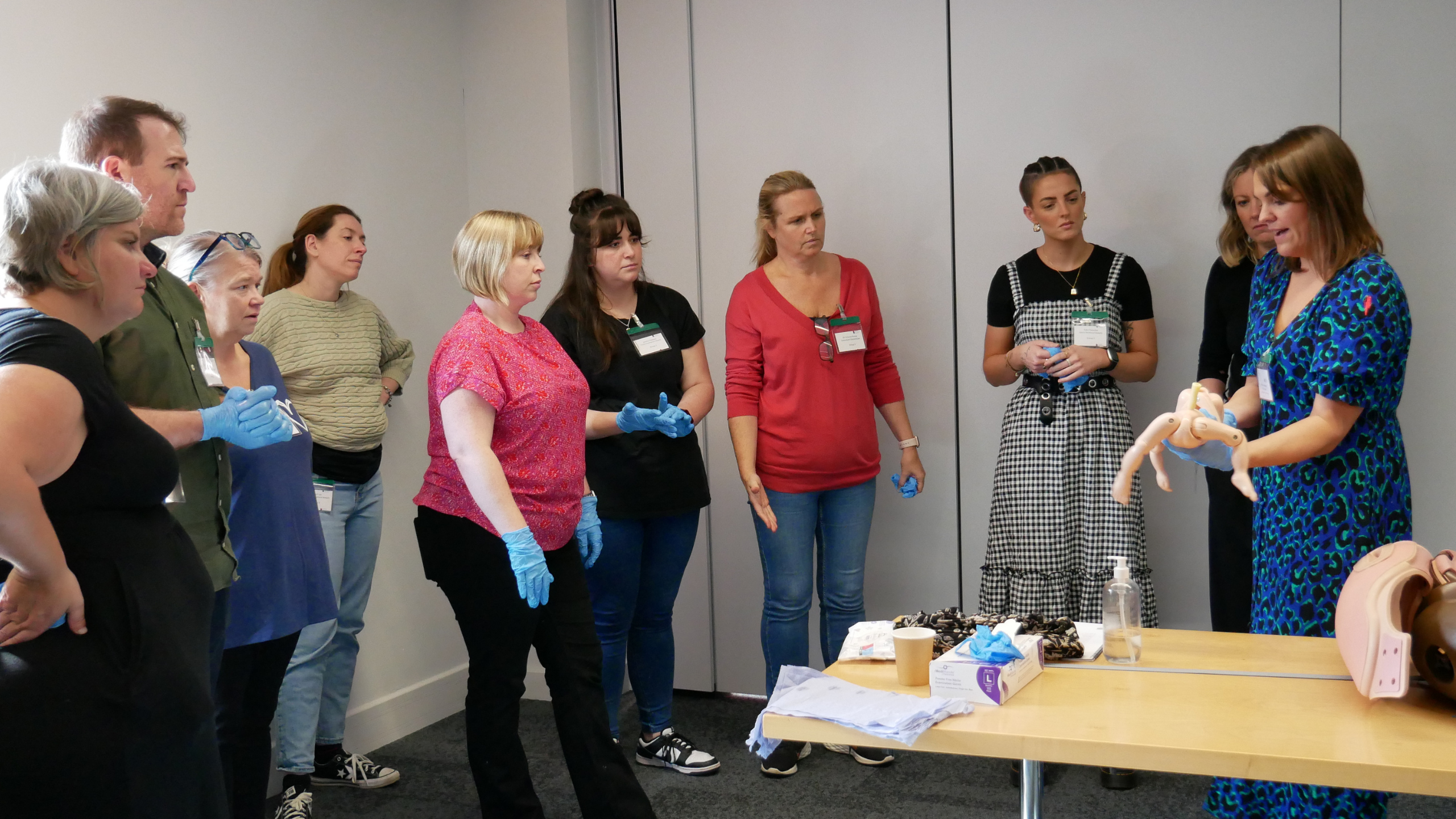 A woman is giving a demonstrating during a training session for the Avoiding Brain Injuries in childbirth programme. Other people are watching her.