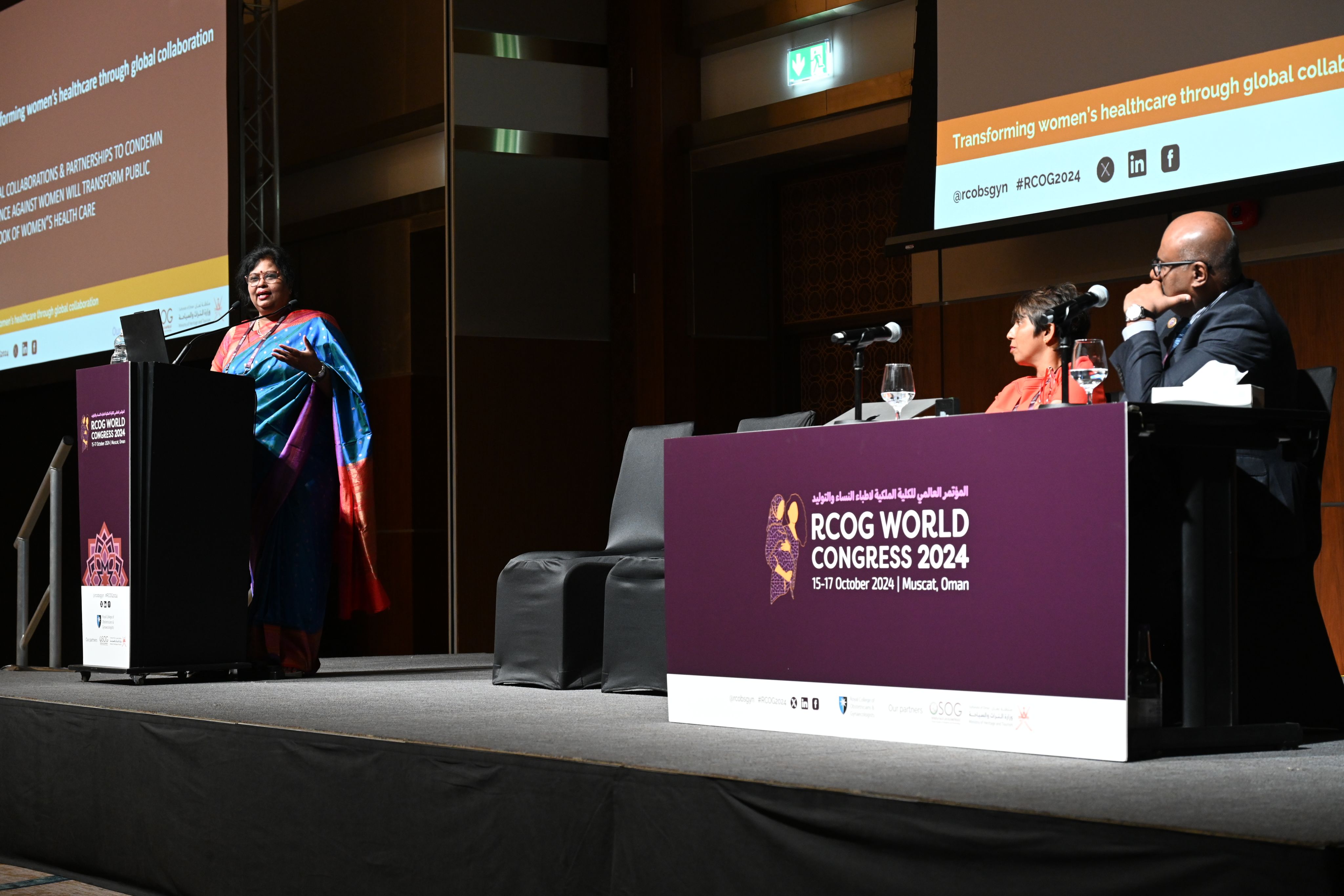 On the left, a woman stands behind a lectern at RCOG World Congress delivering a presentation. On the right, two people are sat behind a larger desk on the stage, watching her.