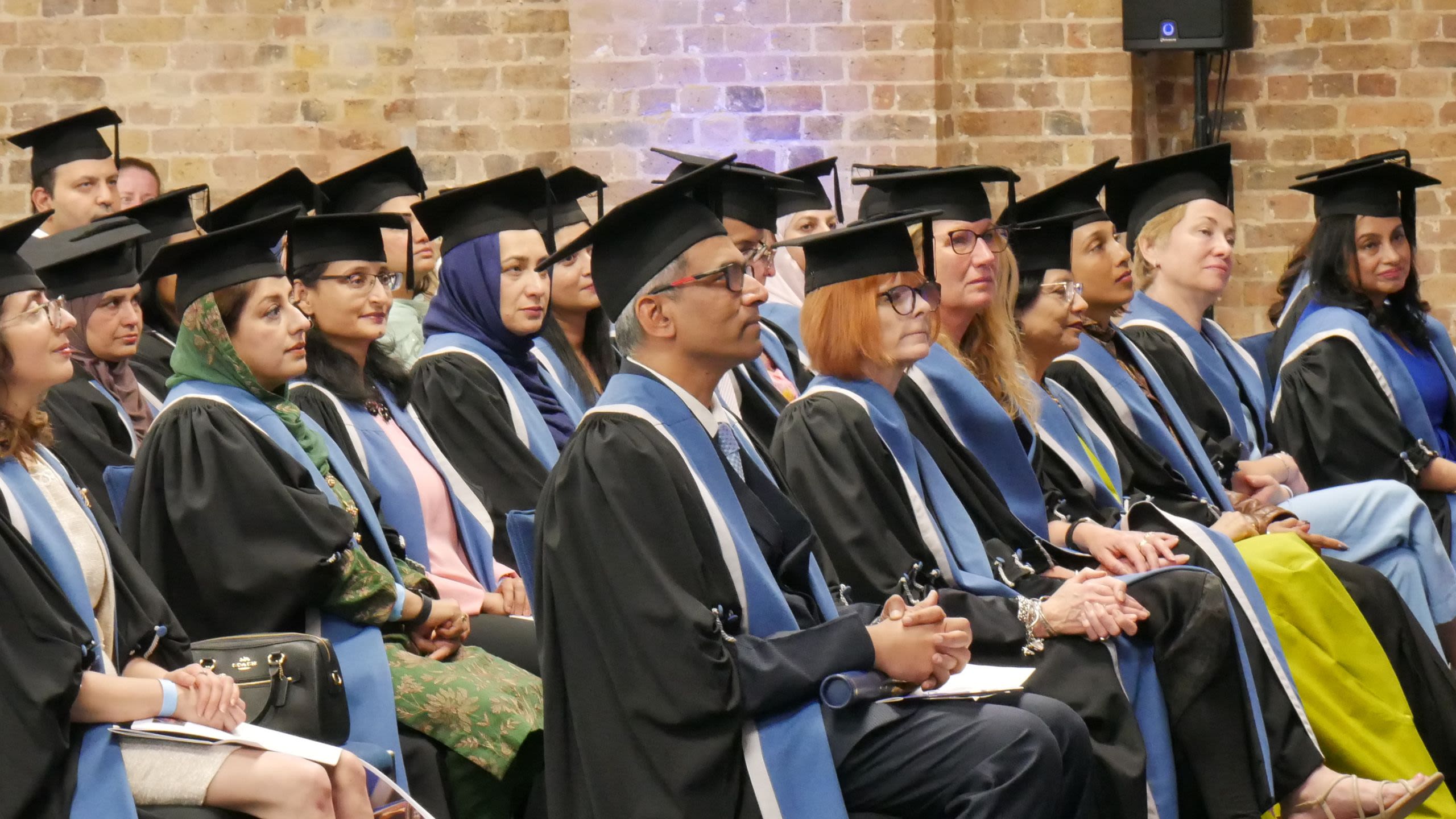 A photo of RCOG members and fellows at an admission ceremony, sitting in rows looking toward the stage