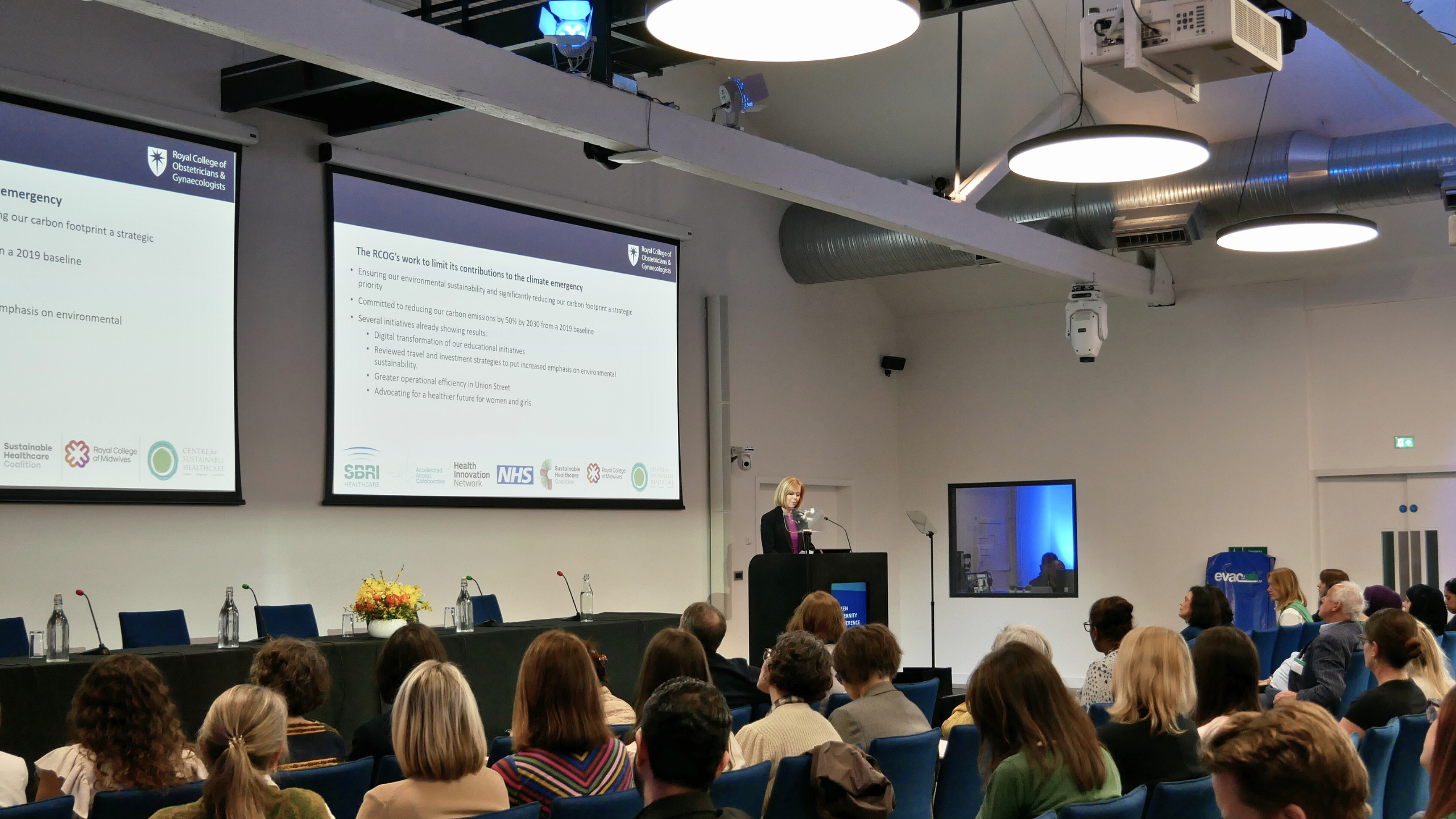 A photo of RCOG Chief Executive Kate Lancaster on stage at an event. The audience are in the foreground.