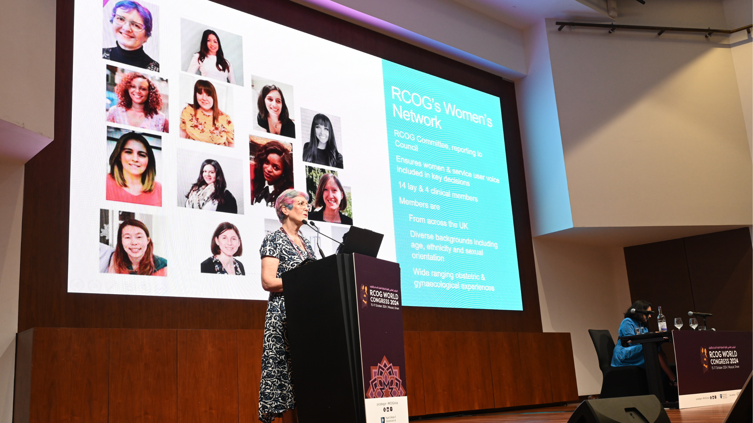 A photo of Jane Plumb, Women's Voices Lead for the RCOG, on stage at RCOG World Congress. She stands behind a lectern with a screen behind her.