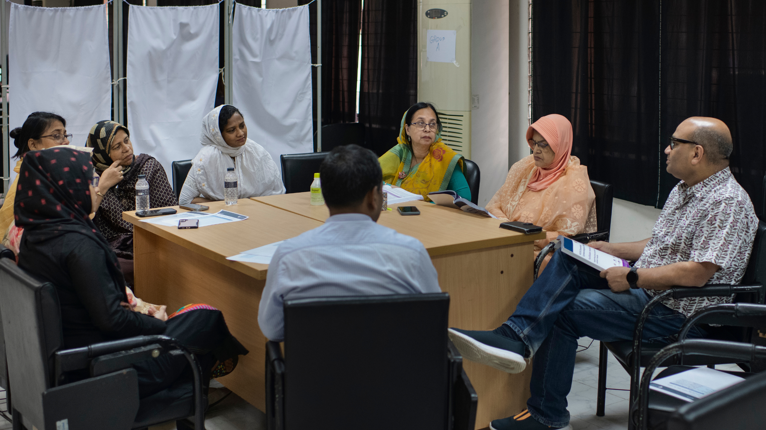 A group of people sitting in a circle at a training session in Bangladesh