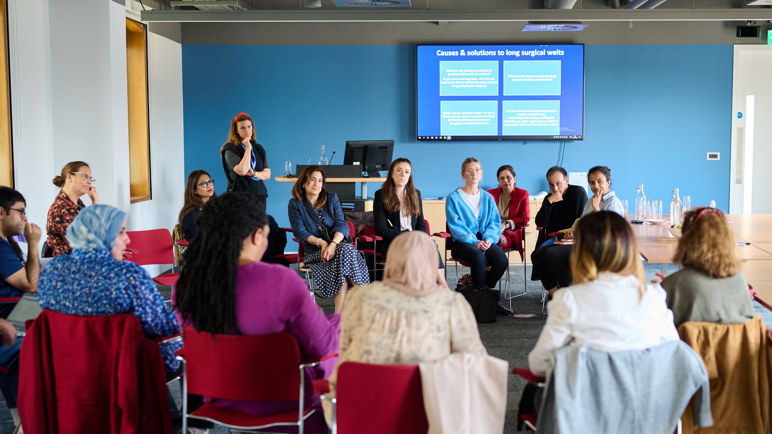 A photo of a focus group, with people sitting in a circle of chairs as they talk to each other