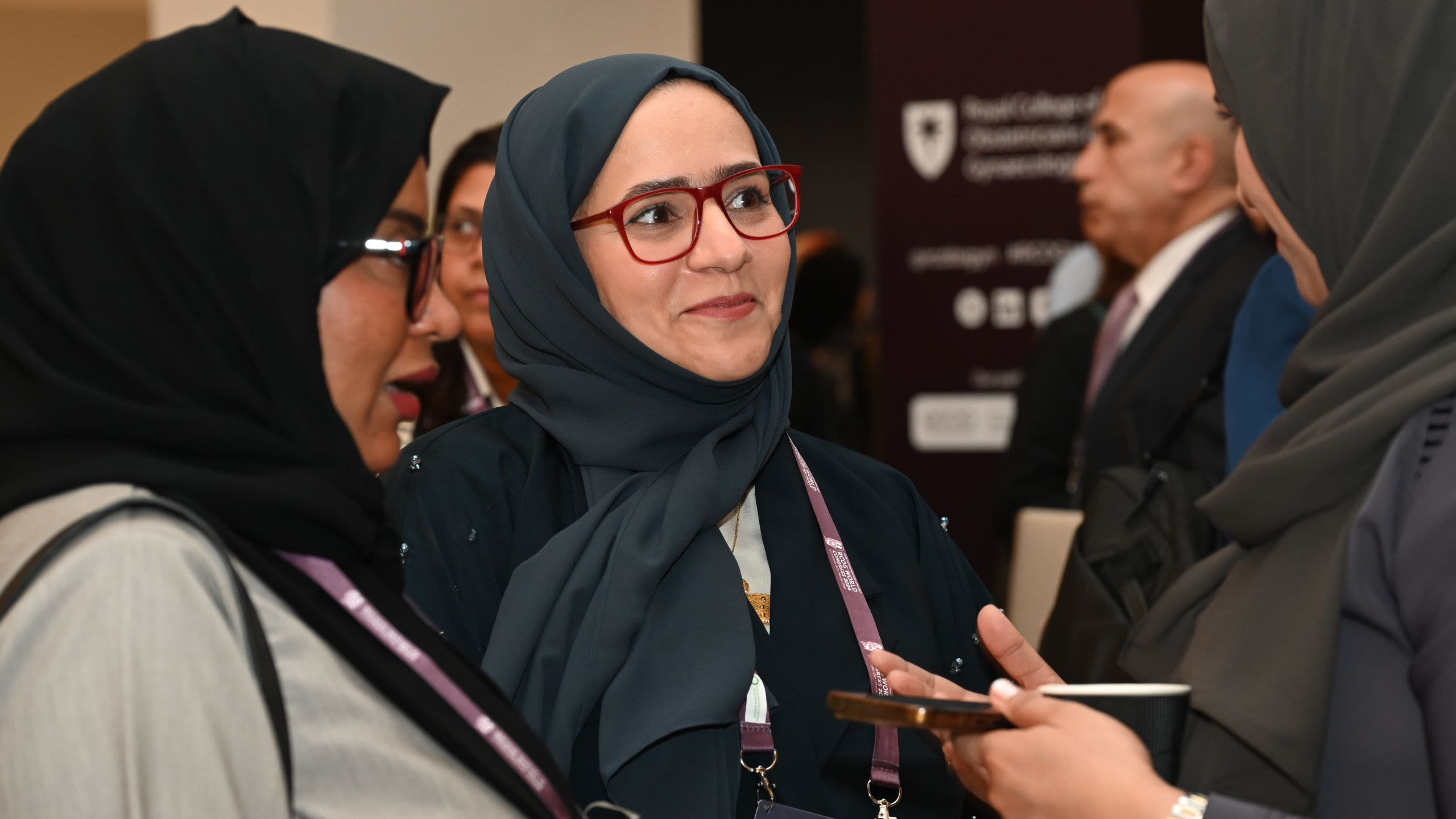 A photo of two women wearing glasses and a heasdcarf, talking to someone out of shot