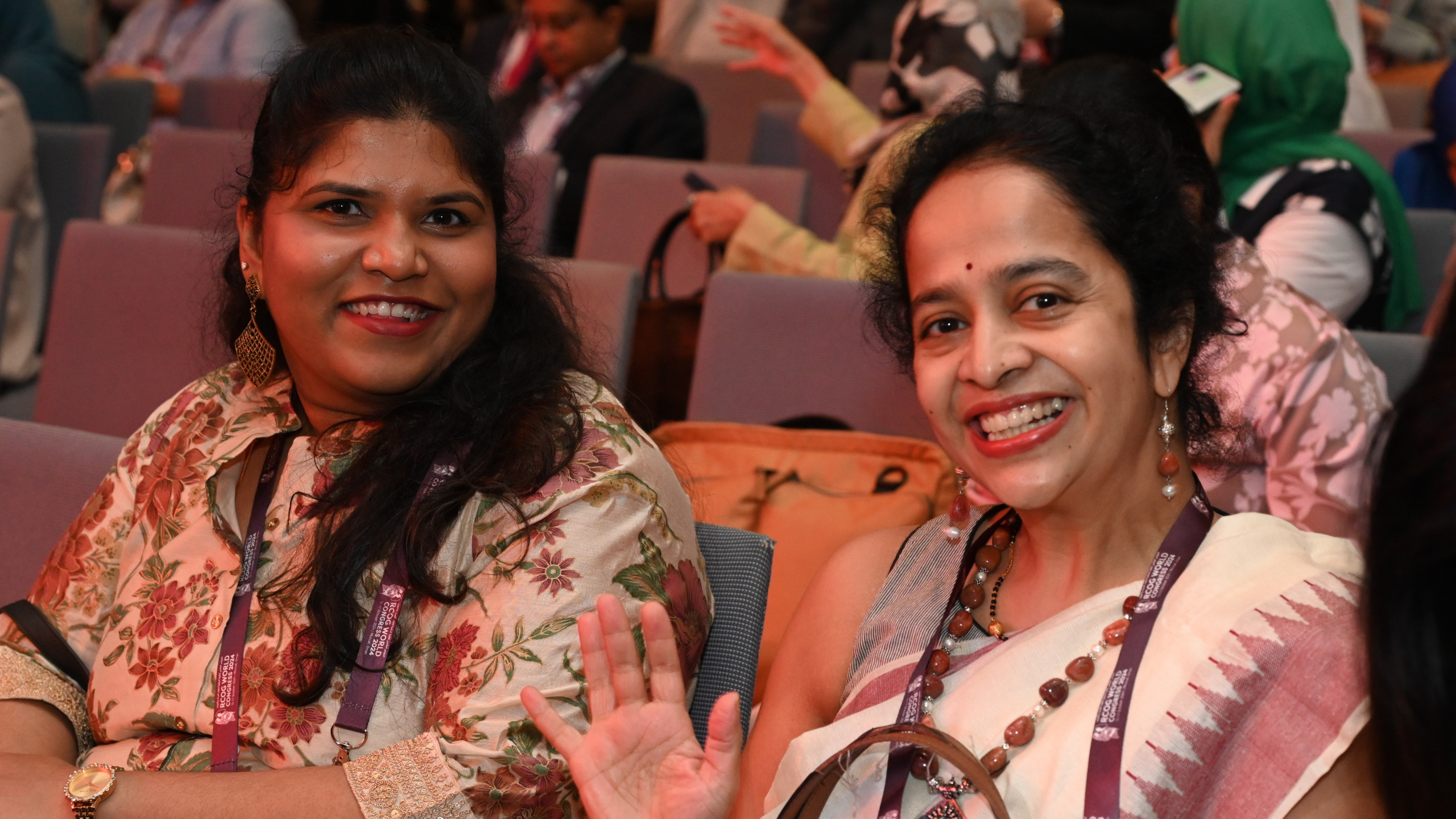 a photo of two women smiling at the camera from their seats in the audience at RCOG World Congress