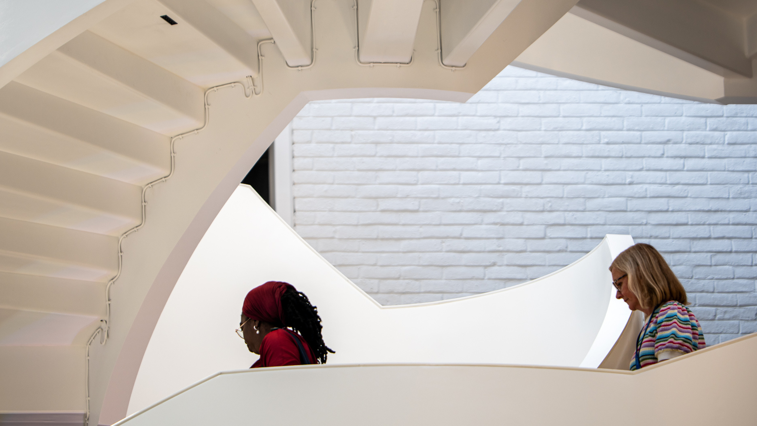 A photo of two people walking down the spiral staircase at the RCOG building in London