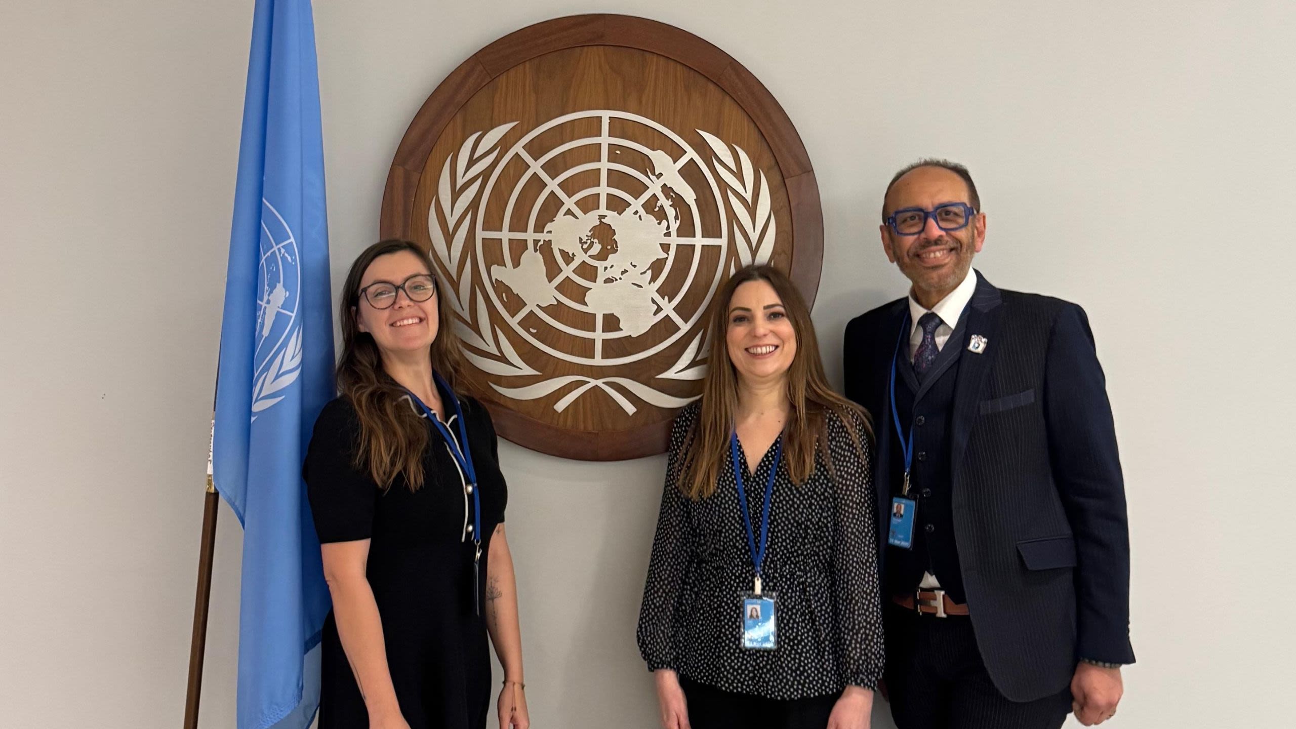 One woman stands on the left of a wooden plaque showing the United Nations symbol. On the right of the plaque are a woman and man. The man is Professor Hassan Shehata, Senior Vice President at the RCOG.