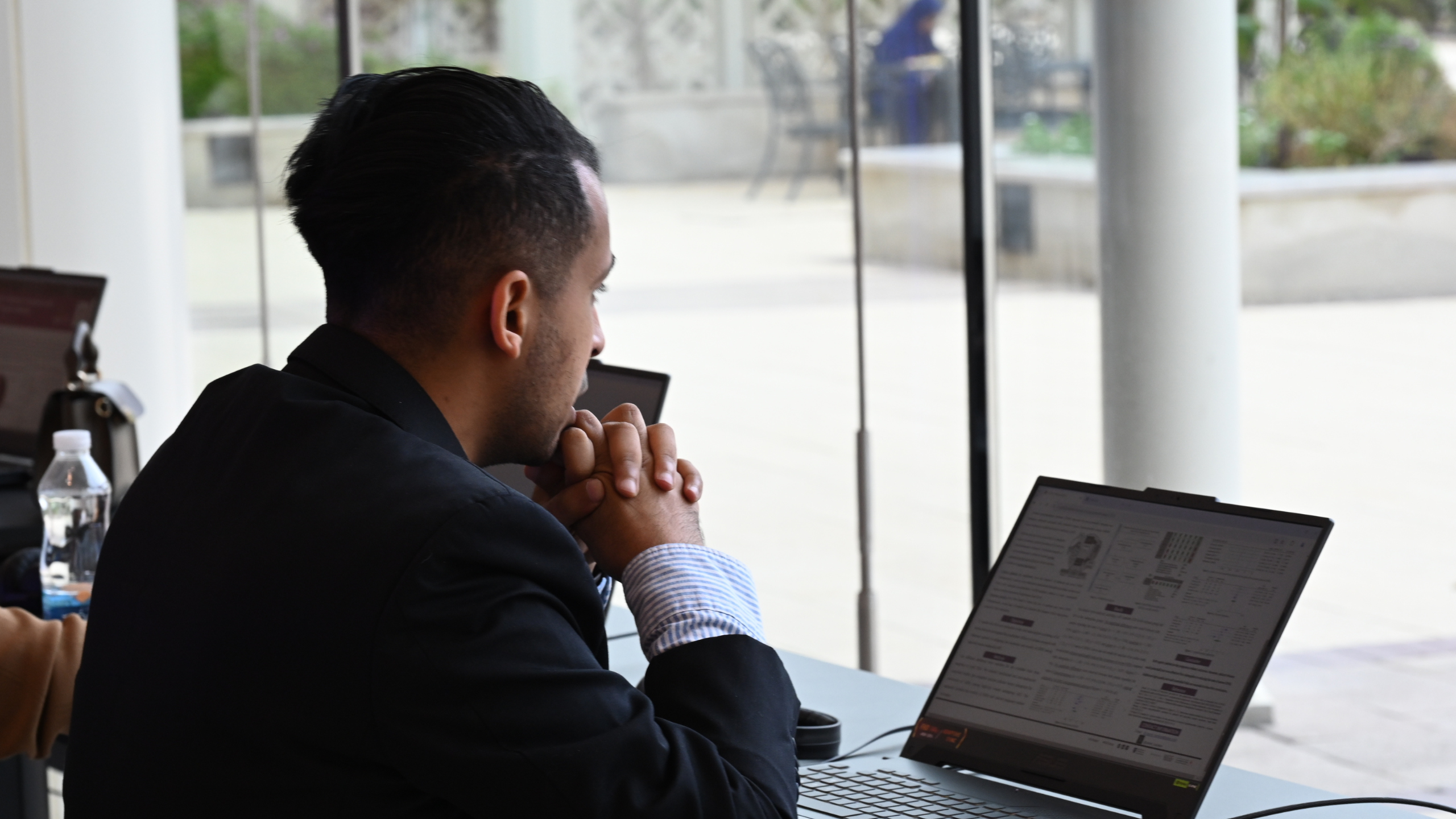 A man sitting down looking a laptop