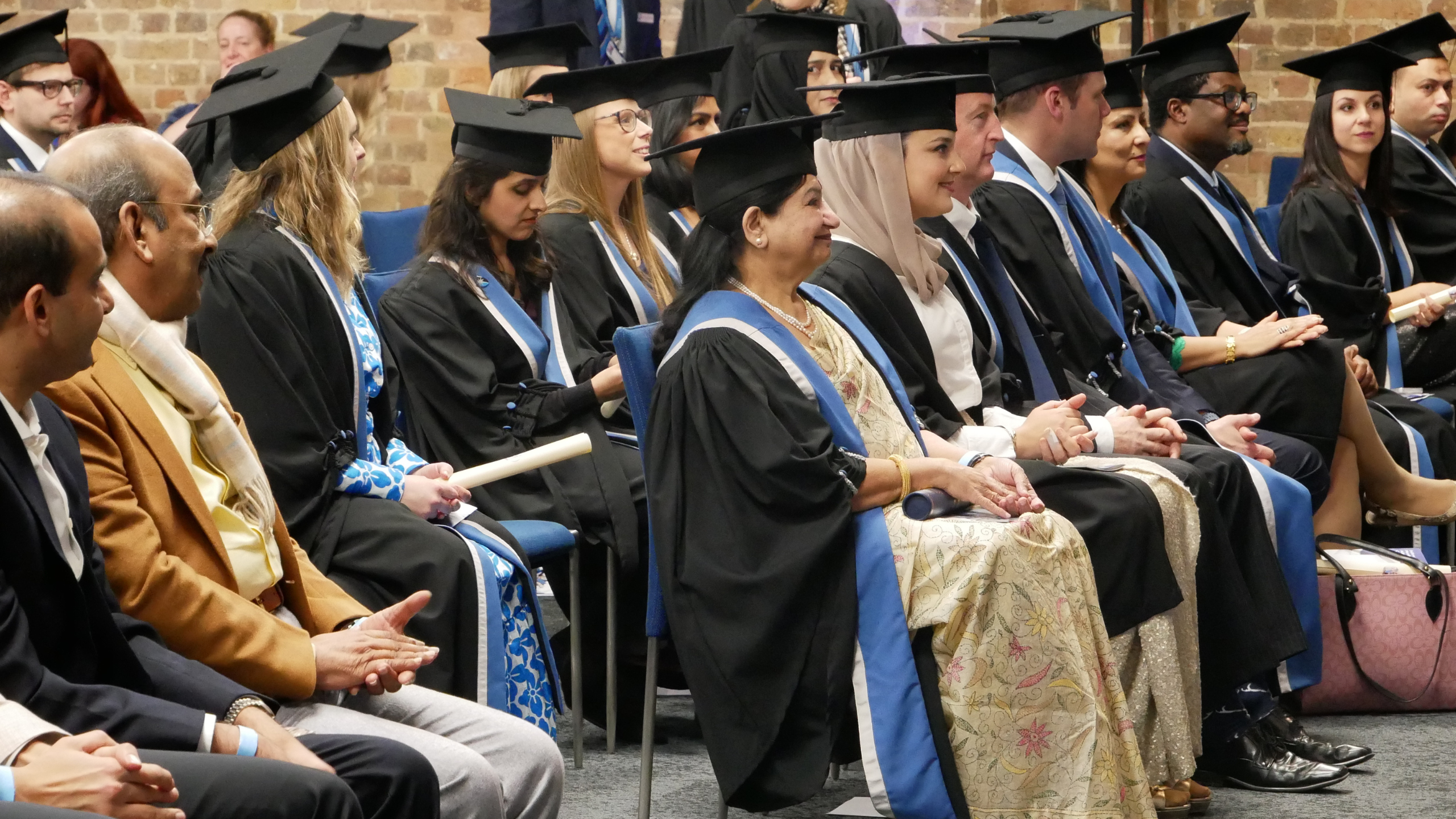Fellows and Members at an admission ceremony, sitting in the audience and looking at the stage. They are wearing gowns and mortarboards