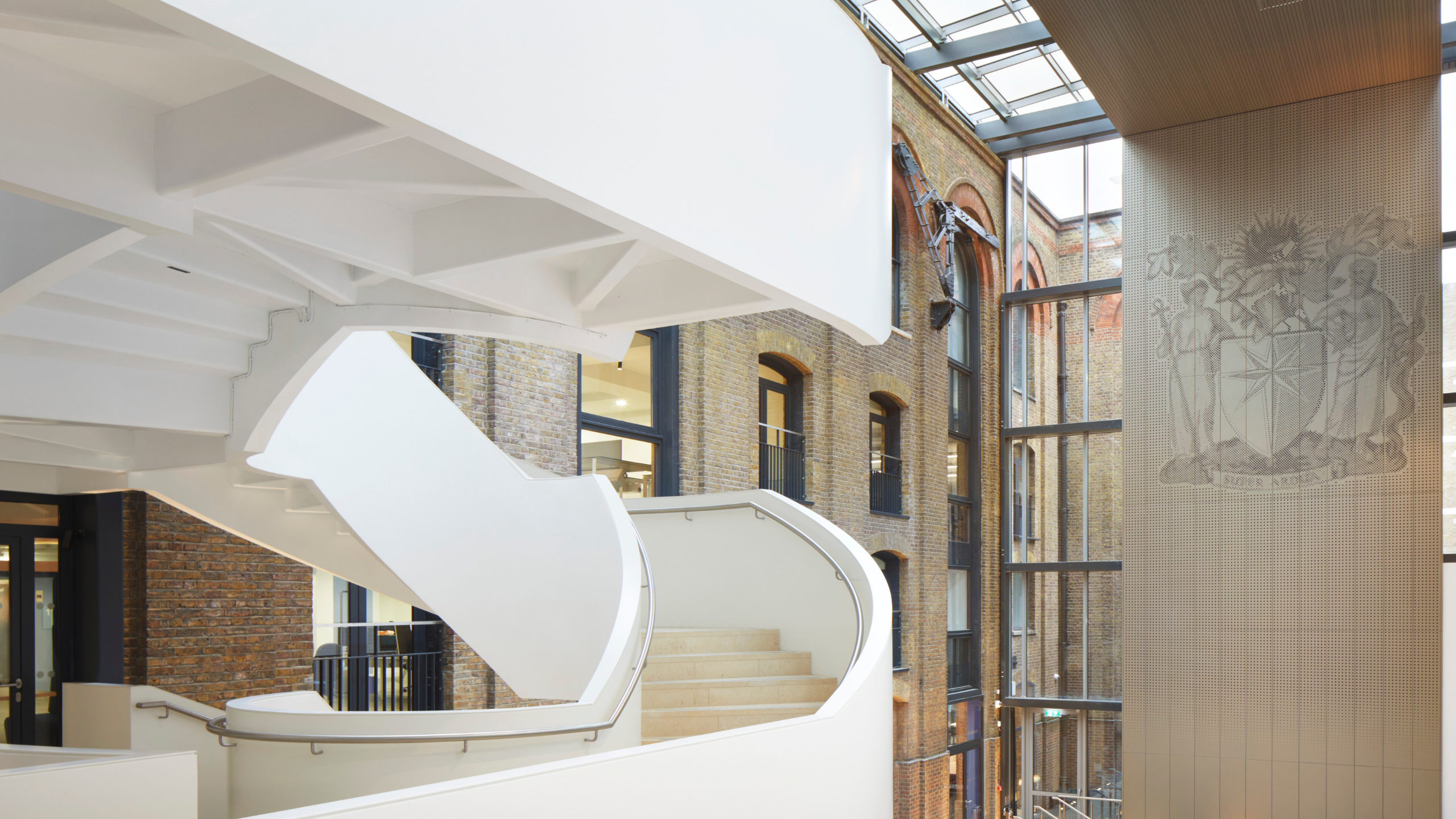 A photo of the RCOG building, with the spiral staircase on the left and wall showing the RCOG coat of arms on the right